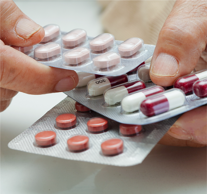 Hands holding multiple blister packs with assorted prescription pills promoting online medicine stock availability and prescription services. 